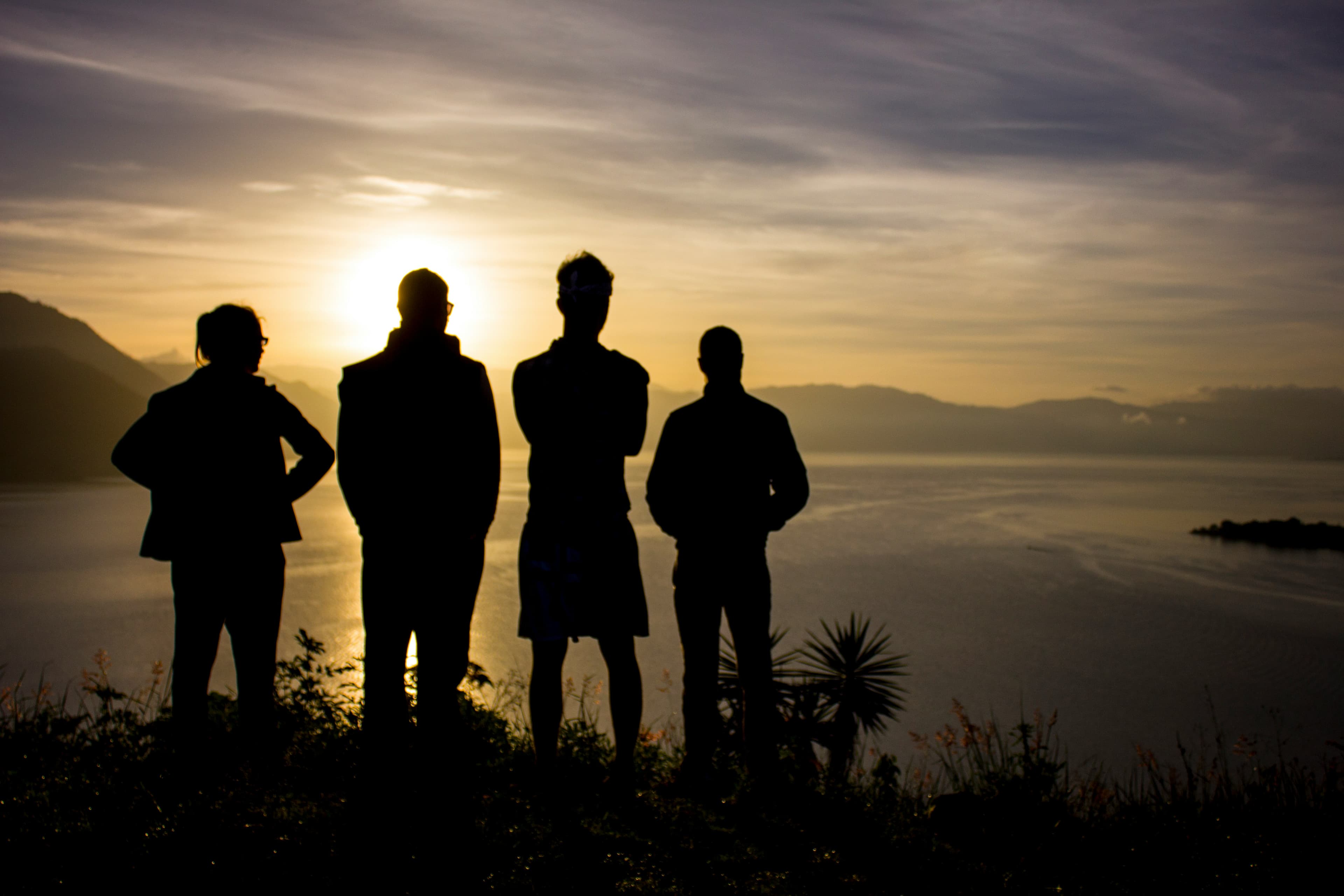 Silhouettes of people standing together at sunset, representing spiritual direction groups and community